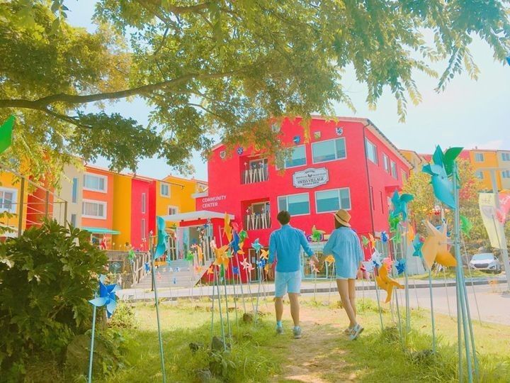 Couple walking through the colorful mini-windmill path at the Swiss Village in Jeju Island. / Dispatch