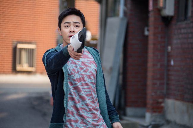 Actor Jo Jung Suk hilariously threatening someone with his slipper for Hyung movie still / Image Source: CJ Entertainment