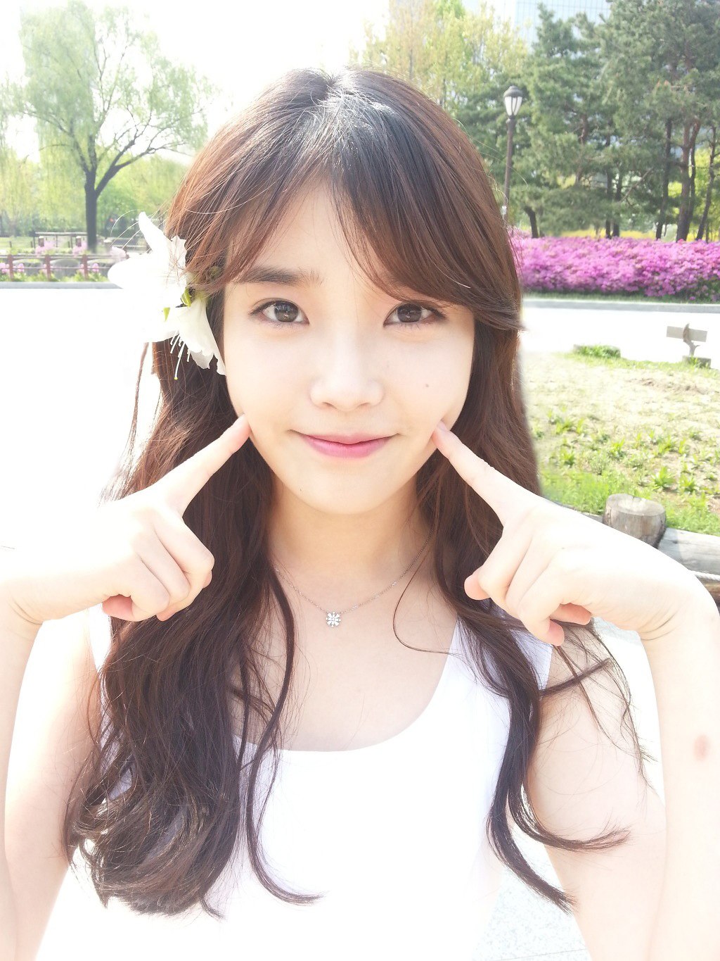 Korean woman with long wavy hair in white sleeveless shirt putting her  hands above her head and looking aside with a smile Stock Photo  Alamy